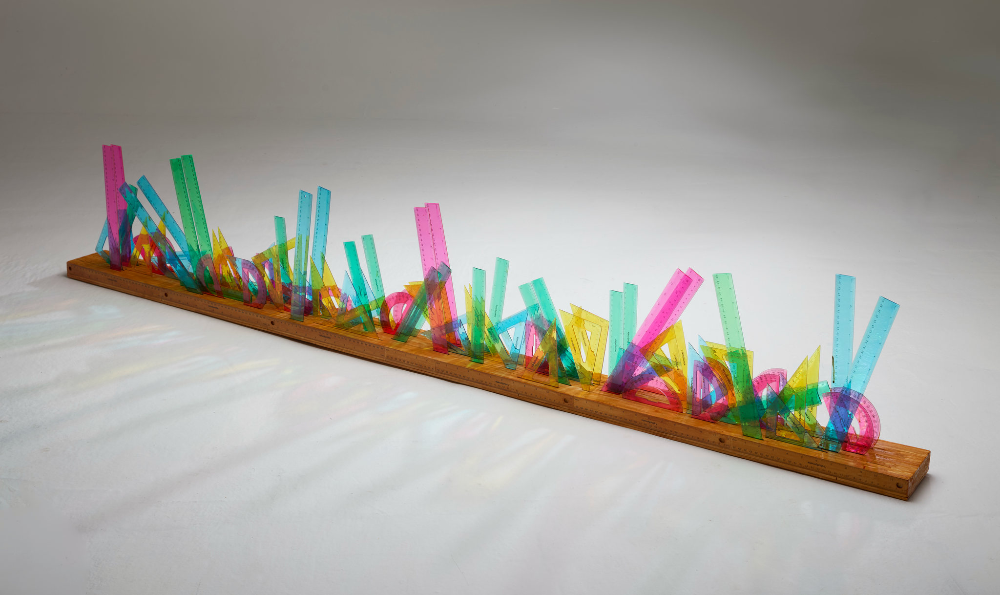 Minaxi May, Infinite Light Crystal, 2026, plastic rulers and wood, 33 x 197.5 x 12cm